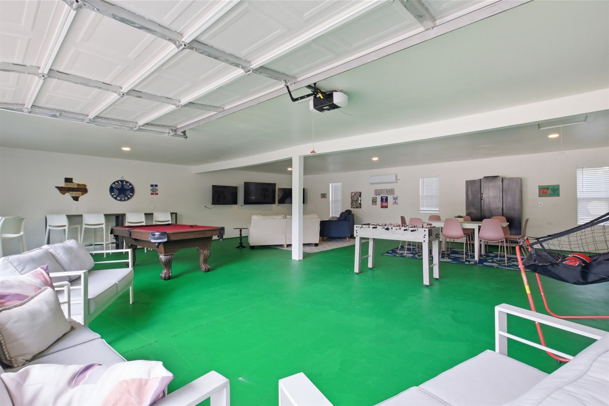 Wide-angle Game Room view showing full 1,000 sq ft layout. Pool Table, Smart TVs, Foosball, and Arcade Games — everything included for group stays near Globe Life Field.