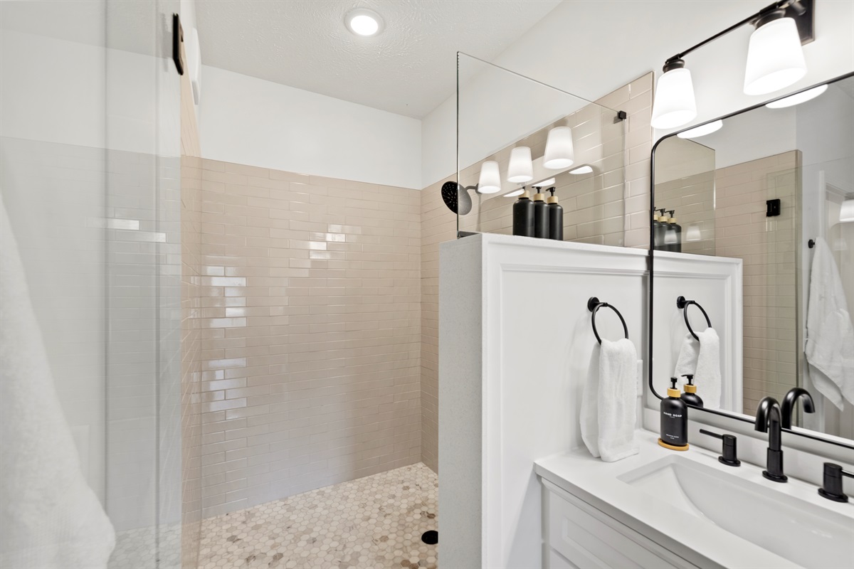 Spacious walk-in shower with glass doors.