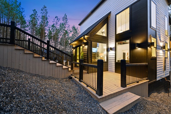 A warmly lit entry welcomes you home, with modern black siding and clean architectural lines.