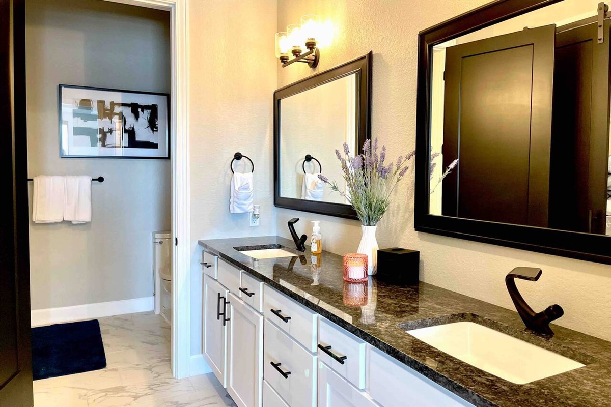 Master bathroom en-suite with double sinks, lots of cabinets, and separate toilet and shower area. 