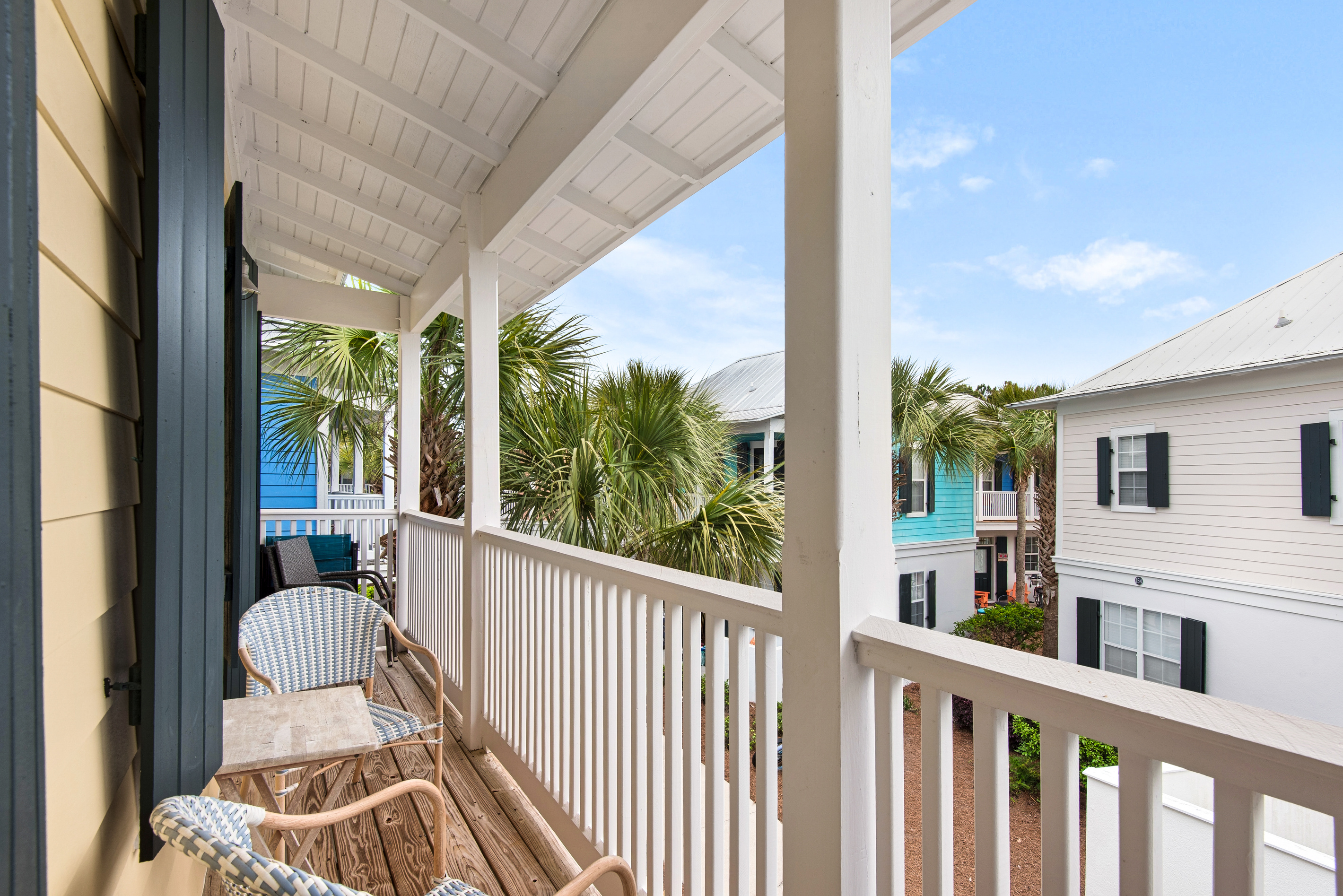 Covered upper balcony at Seagrove Bungalow 103 with outdoor seating and views of the community.