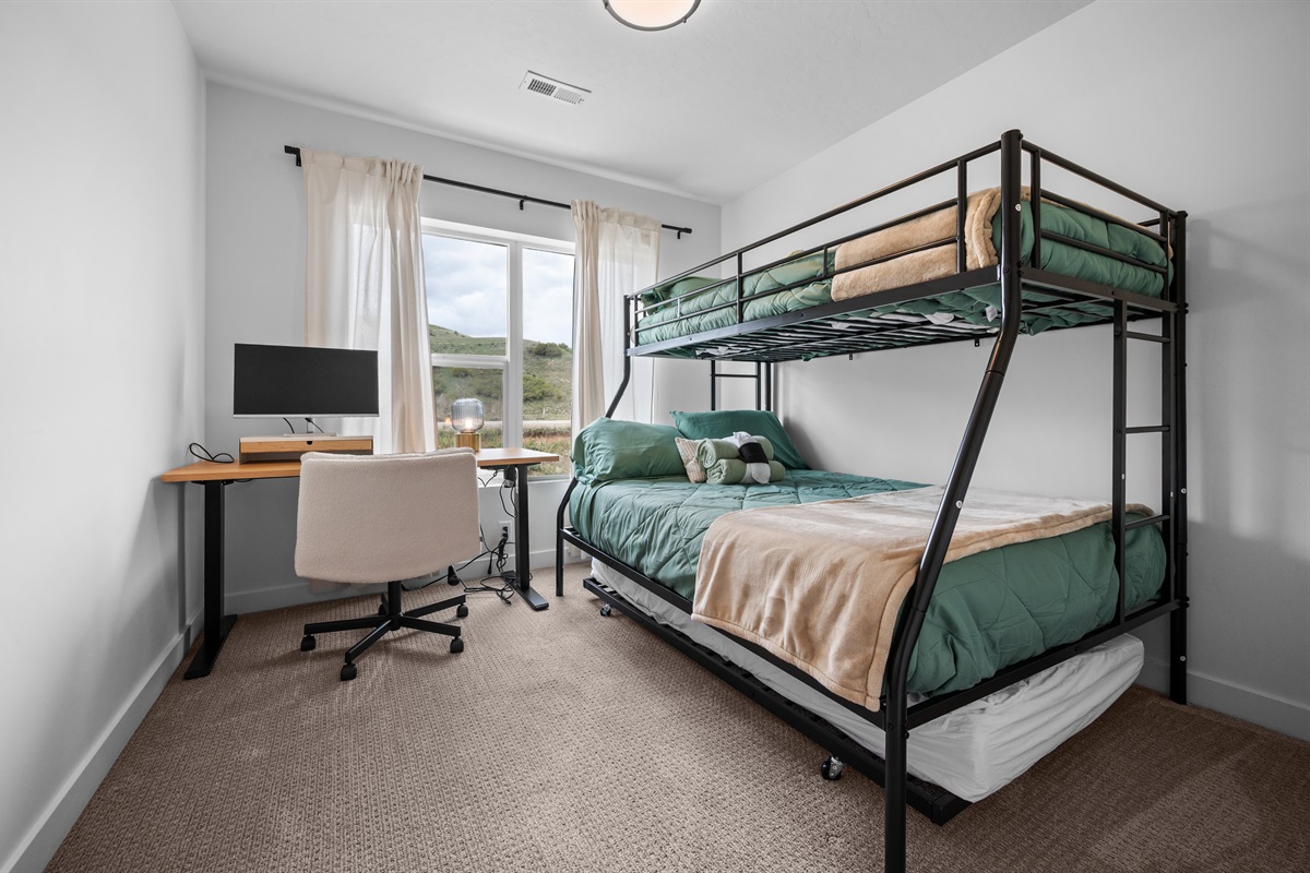 Spacious bunk bedroom with workspace and natural light.