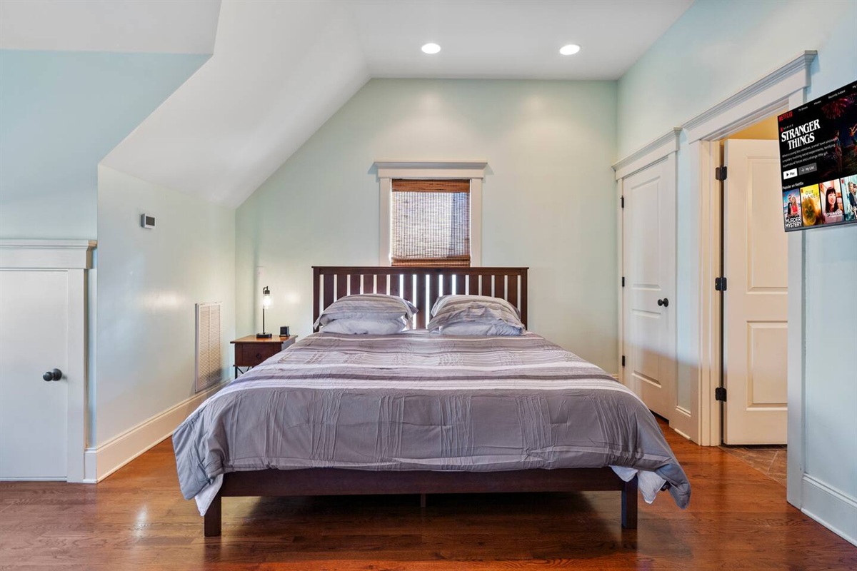Bright studio bedroom area with hardwood floors and easy access to the full bath
