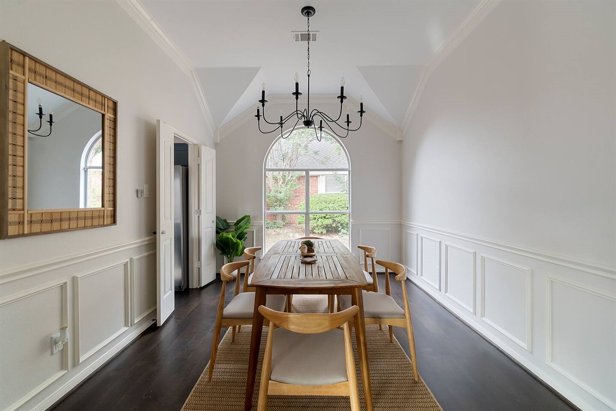 Enjoy a cozy dining area adorned with a wall mirror, inviting in the outdoor scenery through a window at the back.