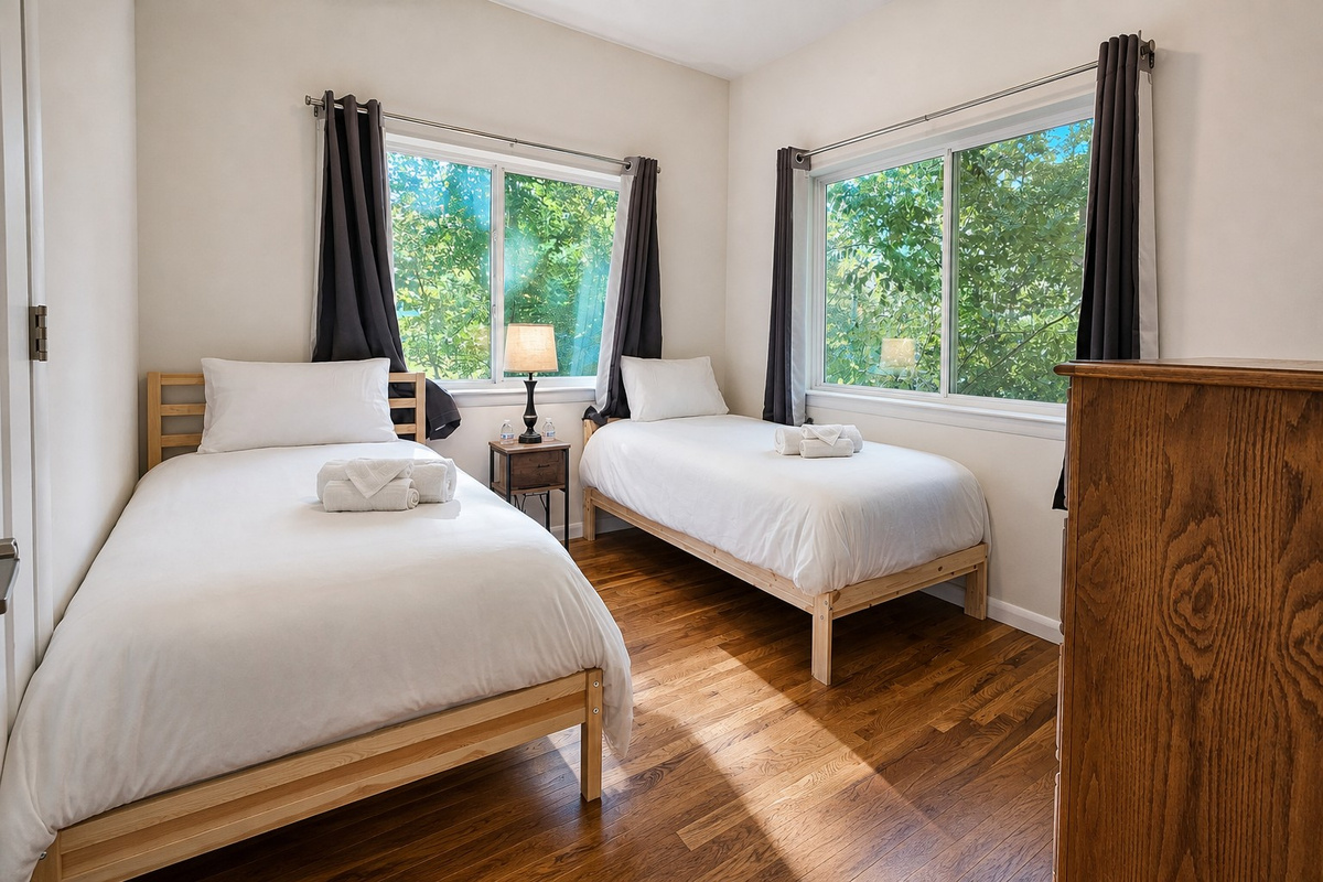 Sunlit bedroom with two twin beds and corner windows