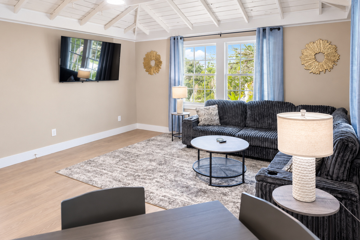 Vaulted‑ceiling living room with gray sectional, sunlit window, and modern décor.
