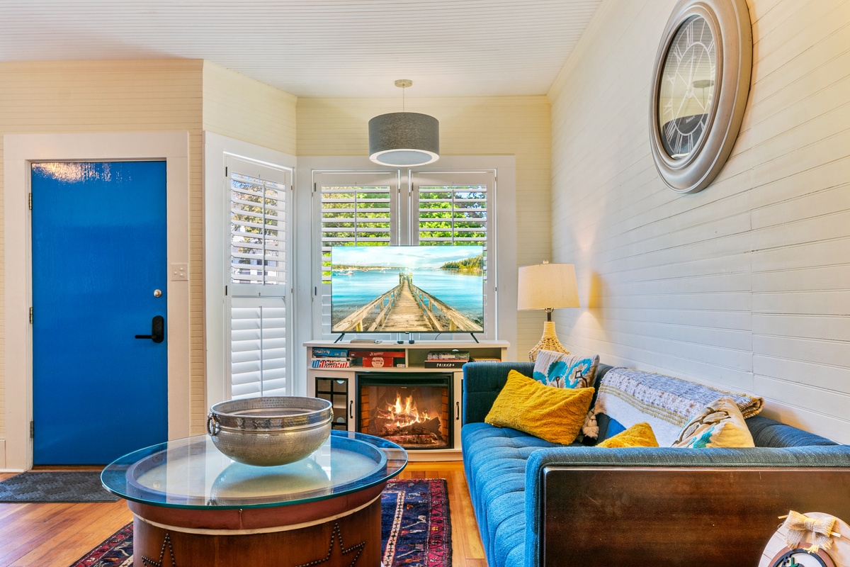 Stepping through the bright blue entry door into the "Quarterdeck" lounge. The 50-inch Roku TV displays the local Southwest Harbor pier, framing a space made for mapping out Acadia adventures by the glow of the electric fireplace.