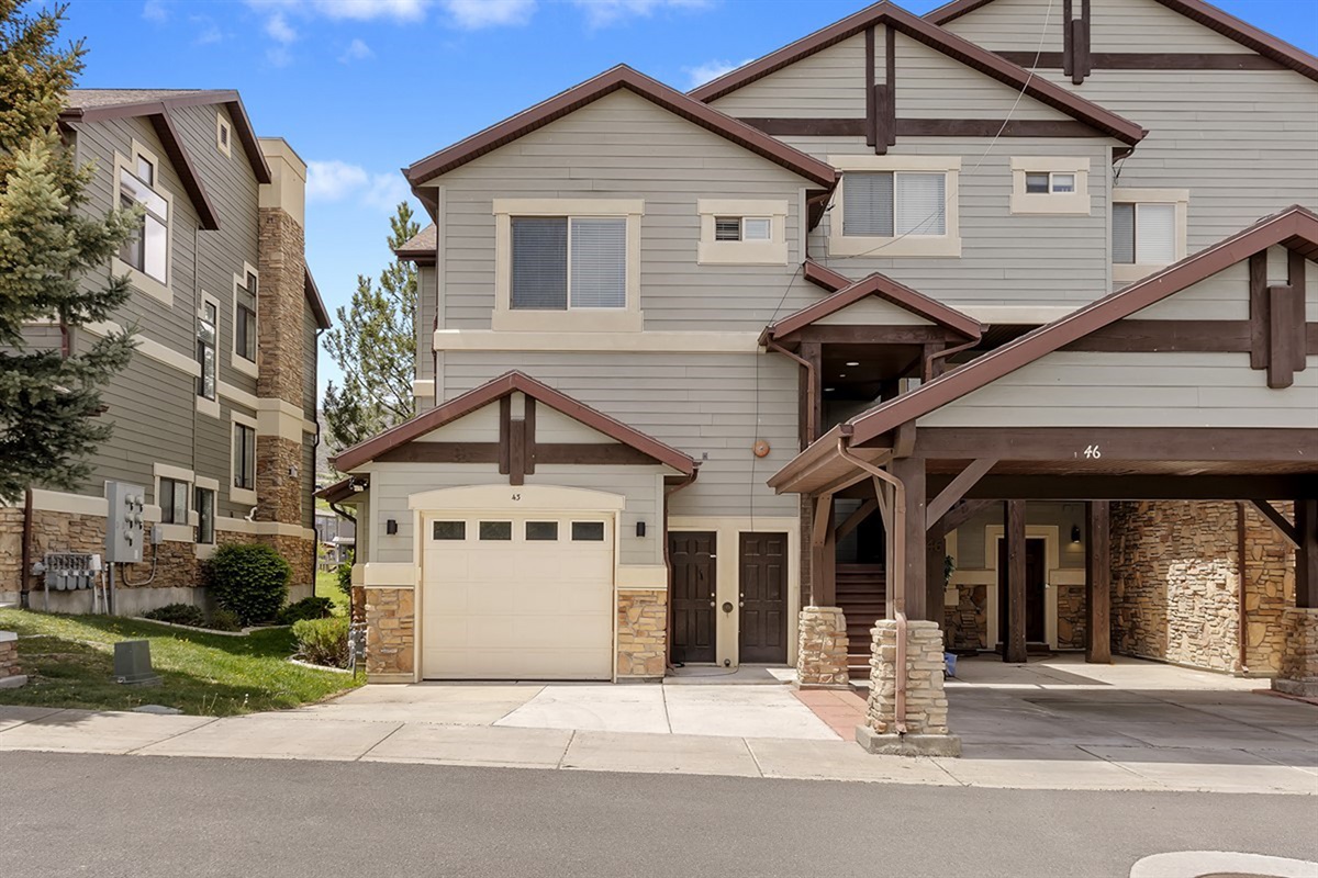 Charming townhome exterior with garage parking, nestled in a scenic mountain community.