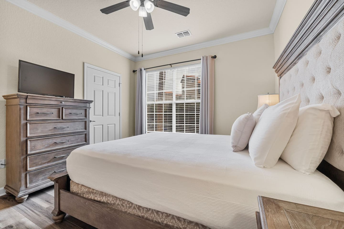 Bedroom 1 features a queen-size bed, a TV, and an abundance of natural light.