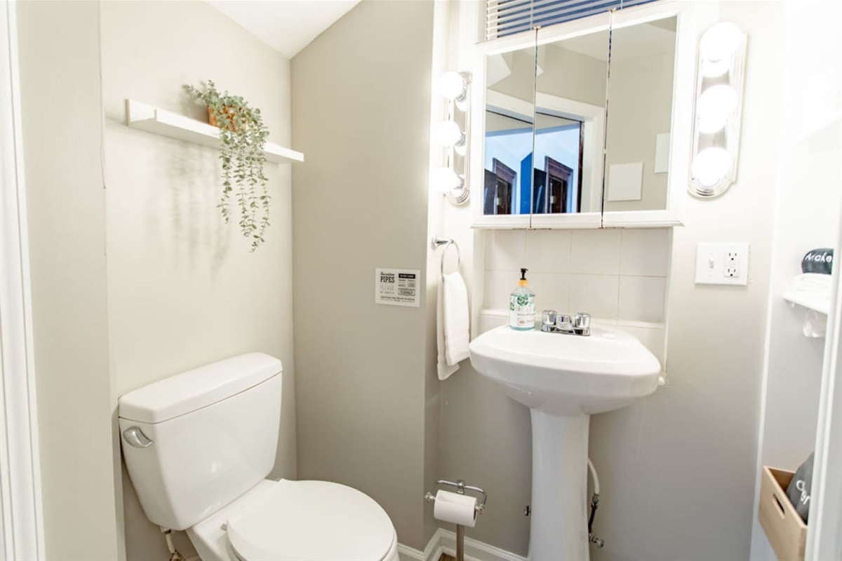 Clean and modern bathroom featuring a spacious toilet, sleek sink, and essential toiletries for your comfort and convenience.