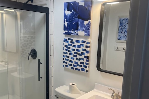 Step into this stylish bathroom featuring a sleek glass shower with black trim, modern vanity, and fun blue-themed decor. Thoughtfully designed for comfort and convenience, it's a fresh and functional space to start or end your day during your stay.