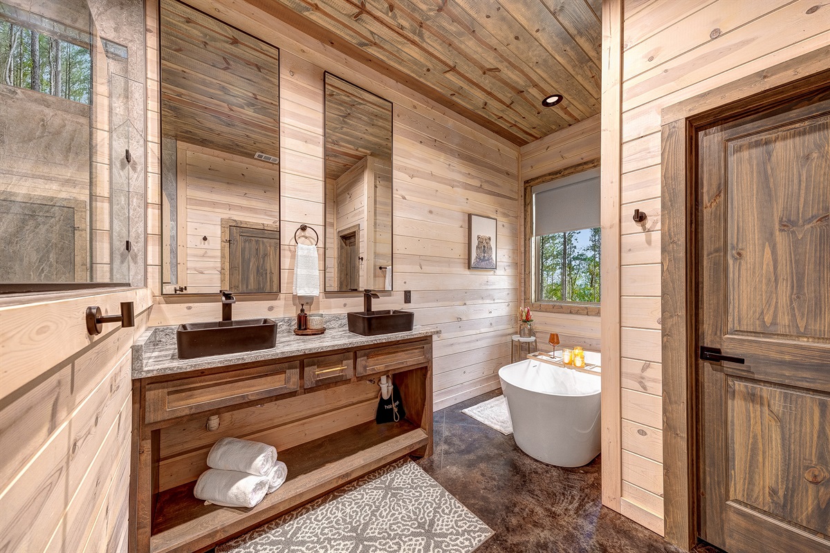Soak away your cares in this deep The master bath is complete with double vanities and luxe black fixtures, this bathroom is a serene escape in the woods.