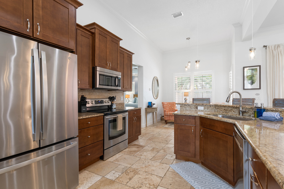 Full kitchen with a large stainless fridge, a dishwasher and long granite counters, with room for a week of groceries.