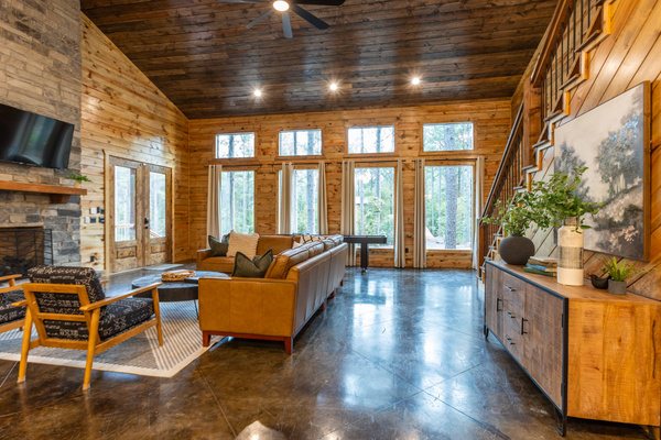 The sun-filled living room features large windows that bring the beauty of the outdoors inside