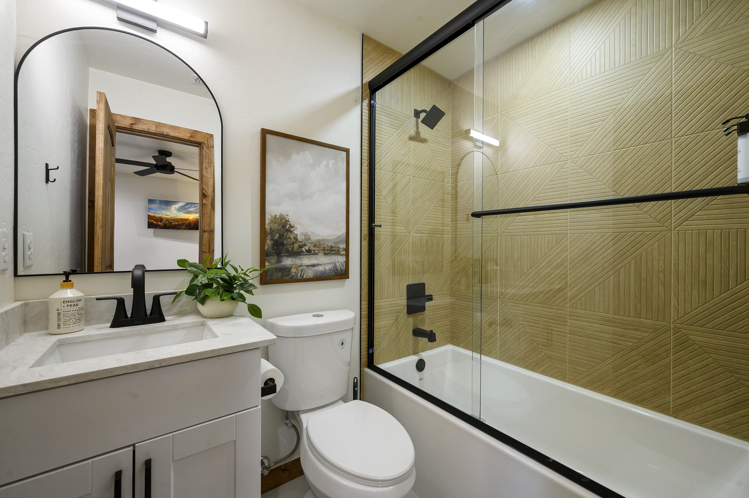 A private ensuite with a tub and shower combination, finished with warm geometric tile and clean modern details.
