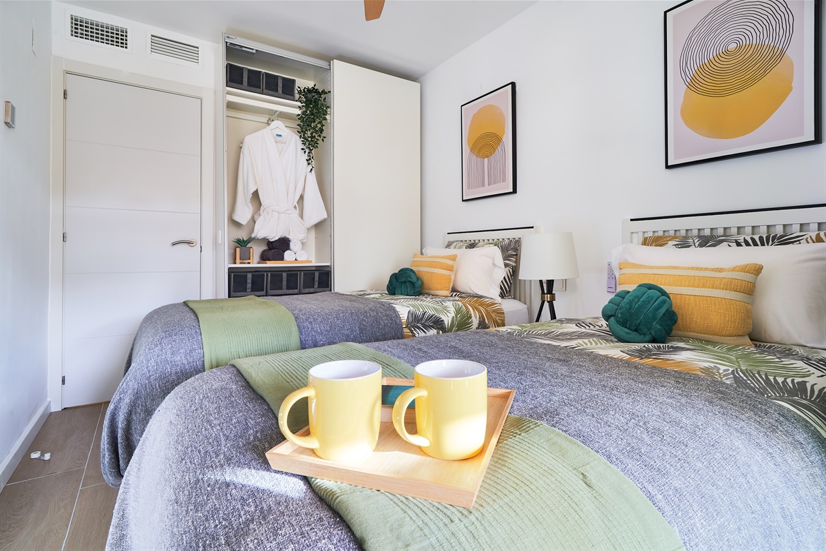 Bright and calming twin bedroom with tropical tones, soft linens, and direct access to the terrace - perfect for relaxed mornings and restful nights.