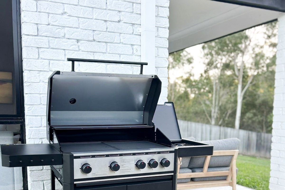 Summers Green View Retreat in Logan Reserve includes a 4-burner gas BBQ set beside the patio and backyard greenery.