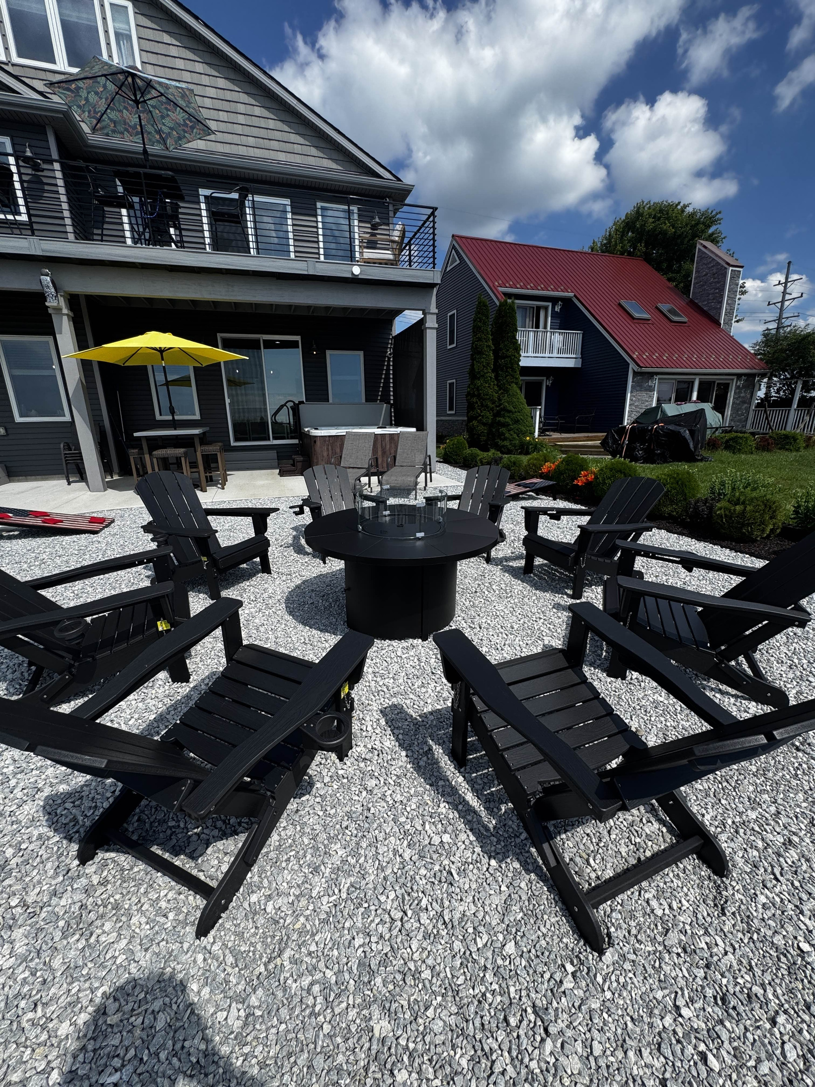 Outdoor fire pit seating area with black lounge chairs on a gravel patio, perfect for relaxing and gathering outdoors.