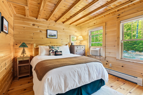 Rest comfortably in this inviting bedroom featuring warm wood interiors and peaceful surroundings.