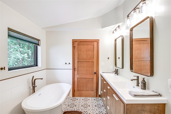 Primary ensuite bathroom with soaking tub, double vanity, and custom tile flooring
