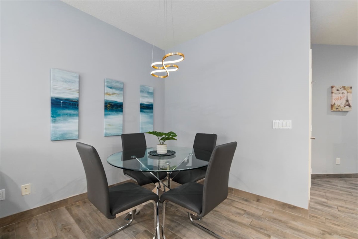 Modern dining area with a glass-top table, stylish chairs, and clean coastal-inspired decor.