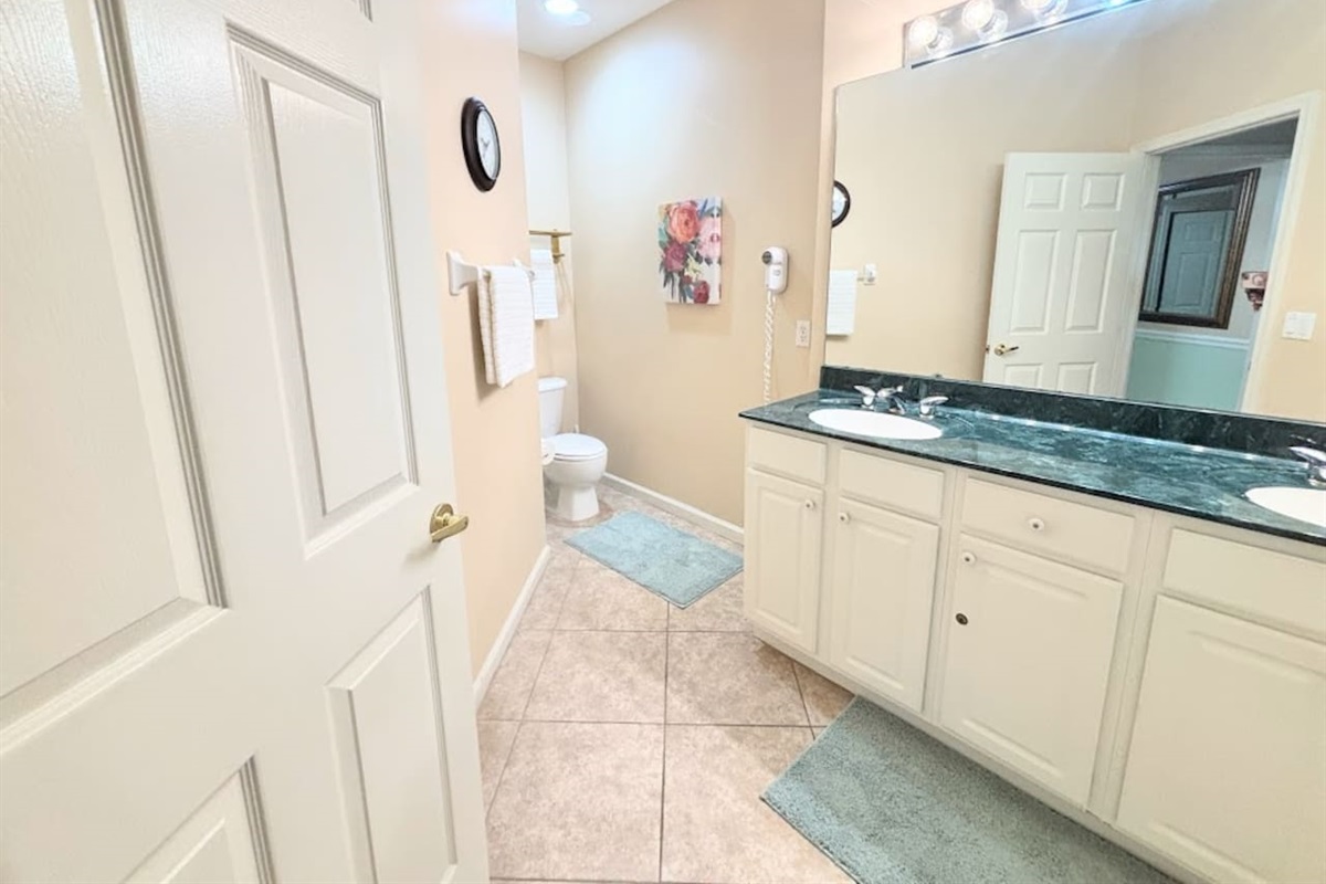 Spacious bathroom featuring a large vanity, tile flooring, and clean neutral finishes.