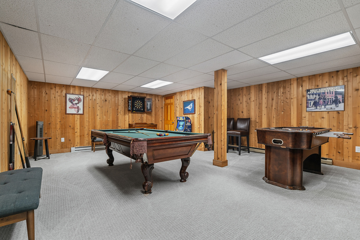 Lower-level game room with billiards and game tables in knotty pine