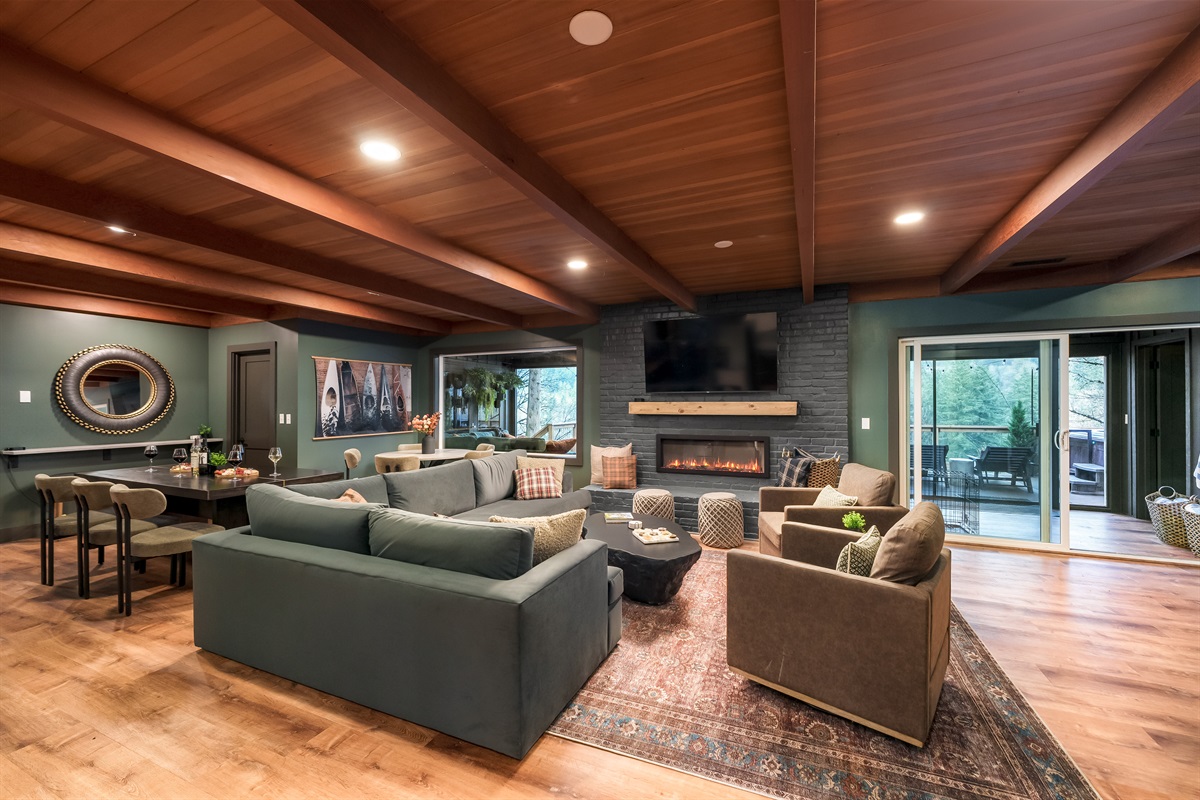Perfect for big gatherings, this spacious living and dining area offers ample seating, a cozy modern fireplace, and easy indoor-outdoor access for everyone to spread out and relax.