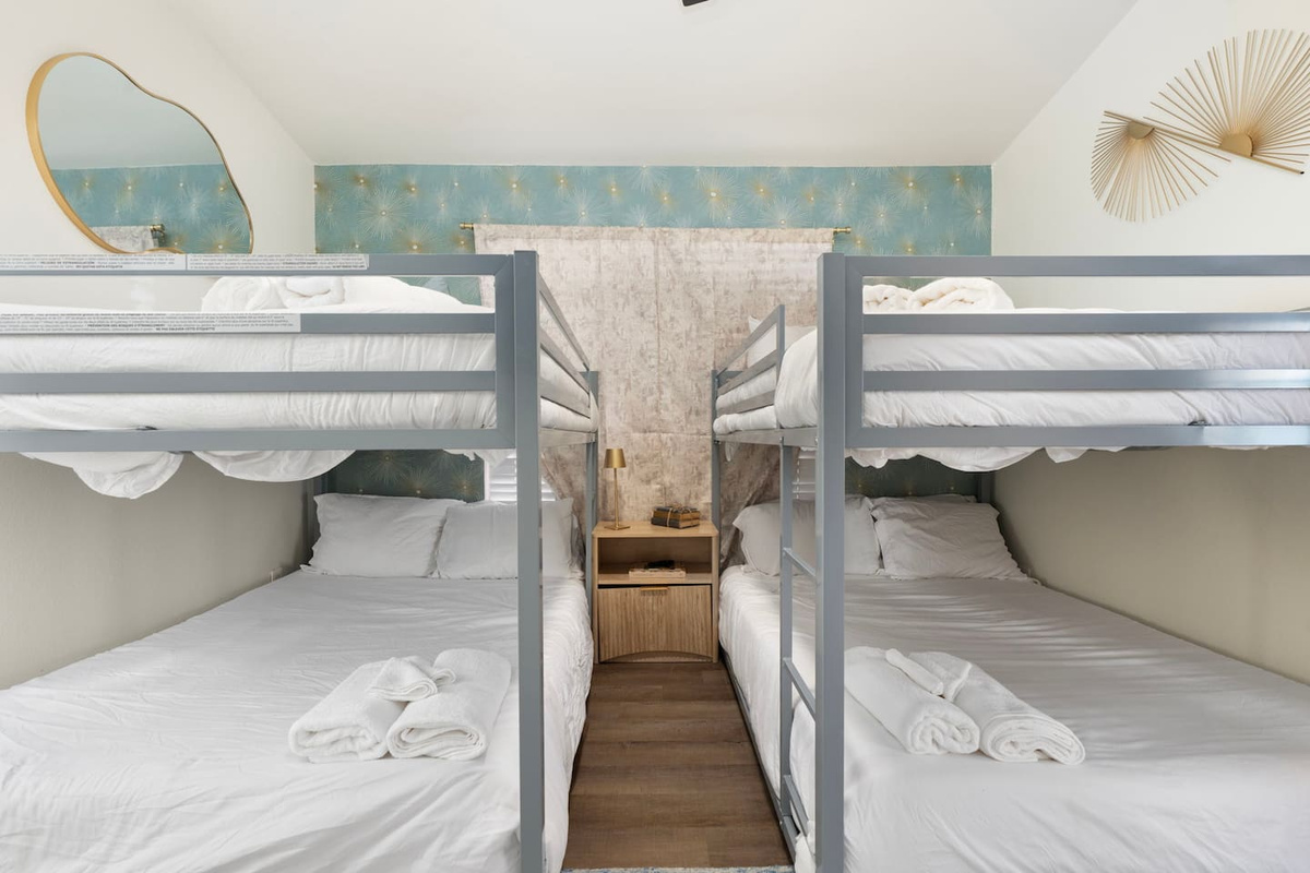 Quad bunk room with soft blue accents, white bedding, and modern finishes—sleeps four guests in comfortable style.