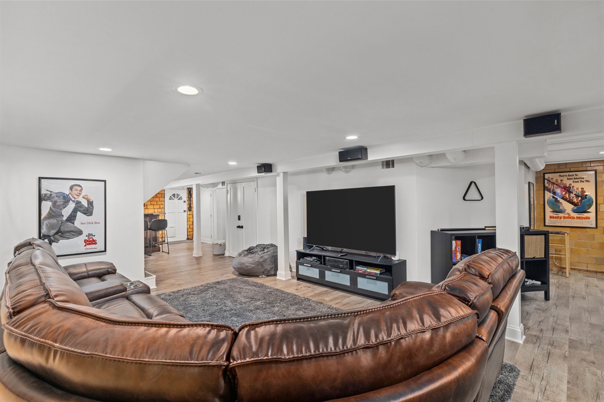 Lower level entertainment room with artificial fireplace, large sectional with 3 power recliners,   75" flatscreen smart TV with surround sound, dry bar, foosball table, air hockey/pool table,