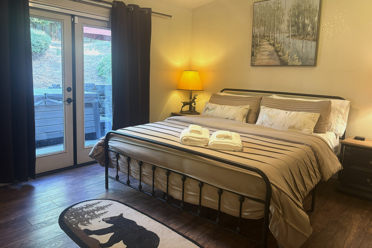 Step into the inviting master bedroom with a king-size bed! This space flows onto an outdoor deck, right next to the hot tub, inviting you to unwind and soak in the tranquil atmosphere.