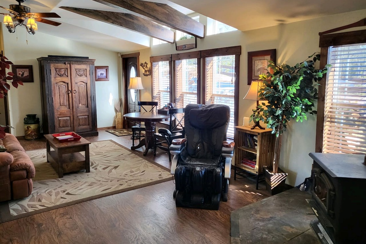 The second living area with a massage chair, wood stove, game table, and an armoire with TV, games, & DVDs
