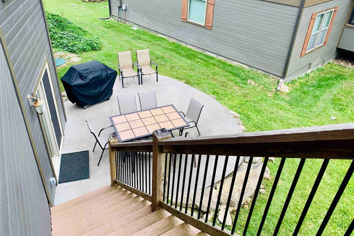 Lower level patio with propane grill, table, and seating 