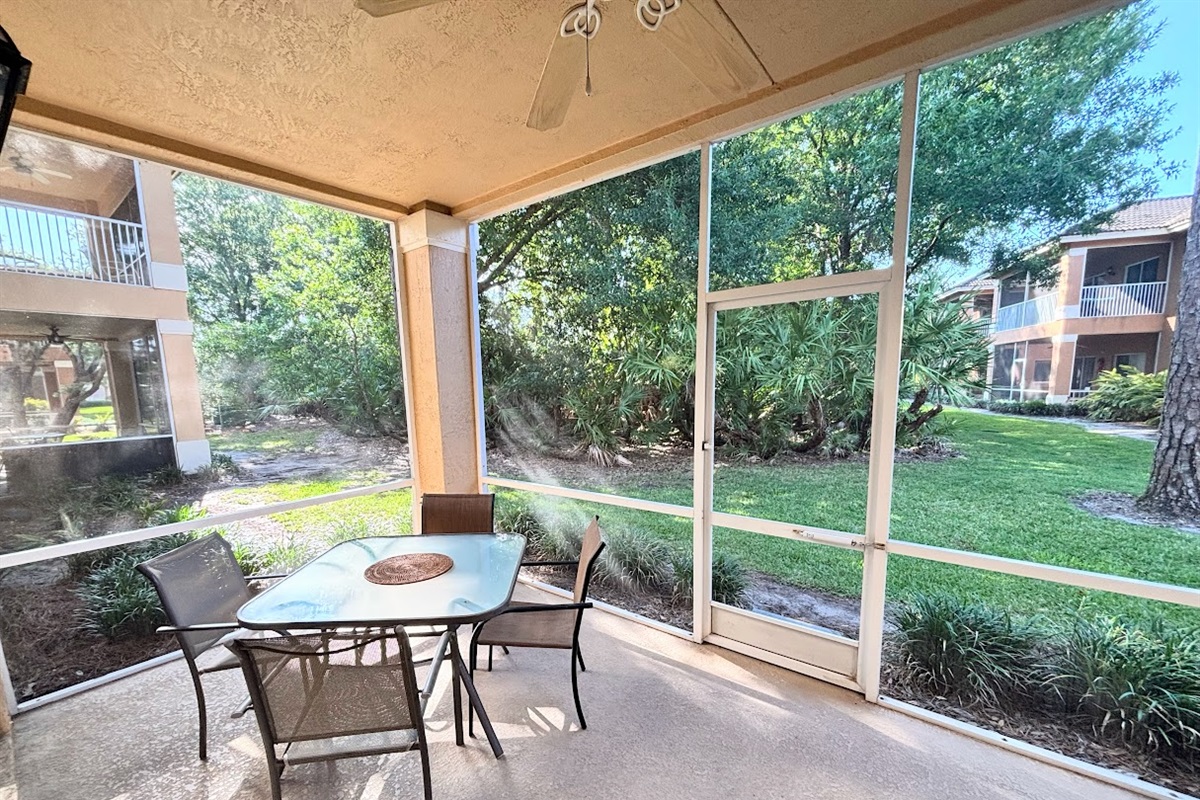 Private screened patio with outdoor seating and peaceful views of the surrounding green space.
