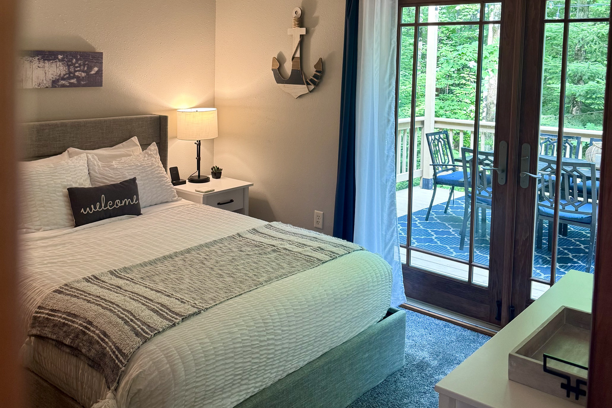 Main Cottage Bedroom view to back deck, with provided breakfast tray, two wireless phone charging stations. French doors plenty of light 