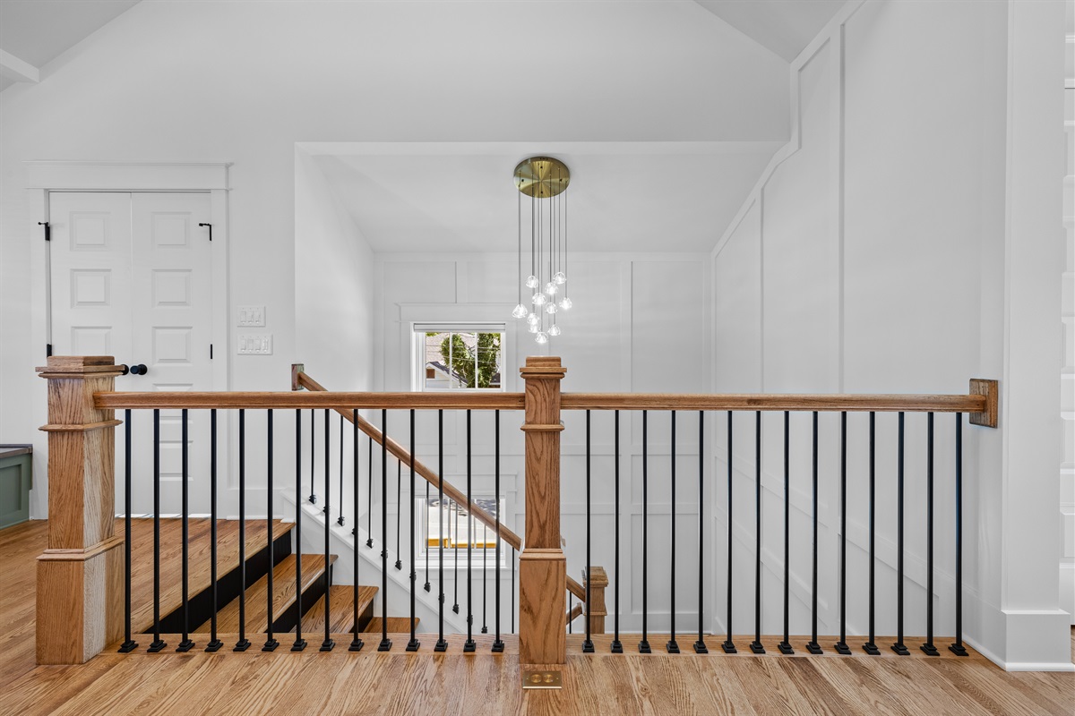 Modern staircase with custom millwork and a statement chandelier.