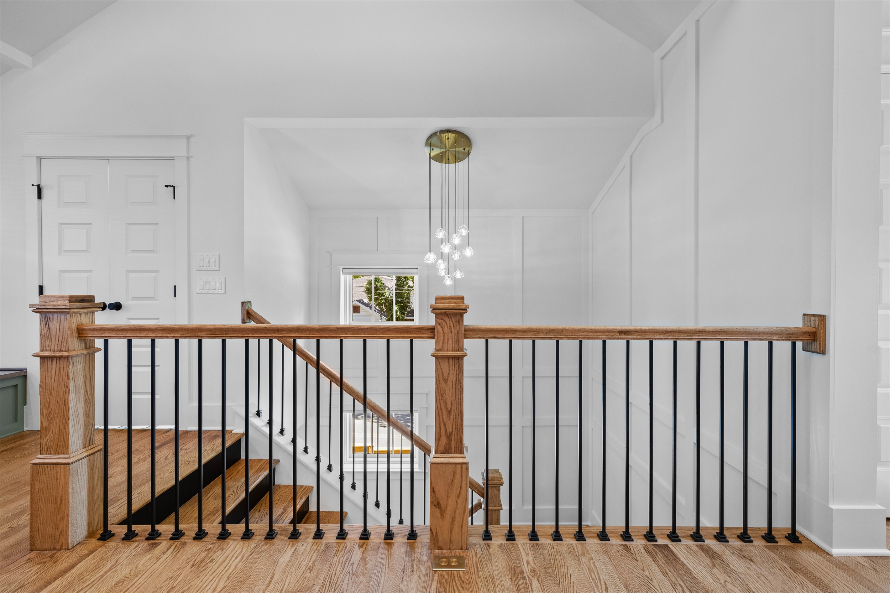 Modern staircase with custom millwork and a statement chandelier.