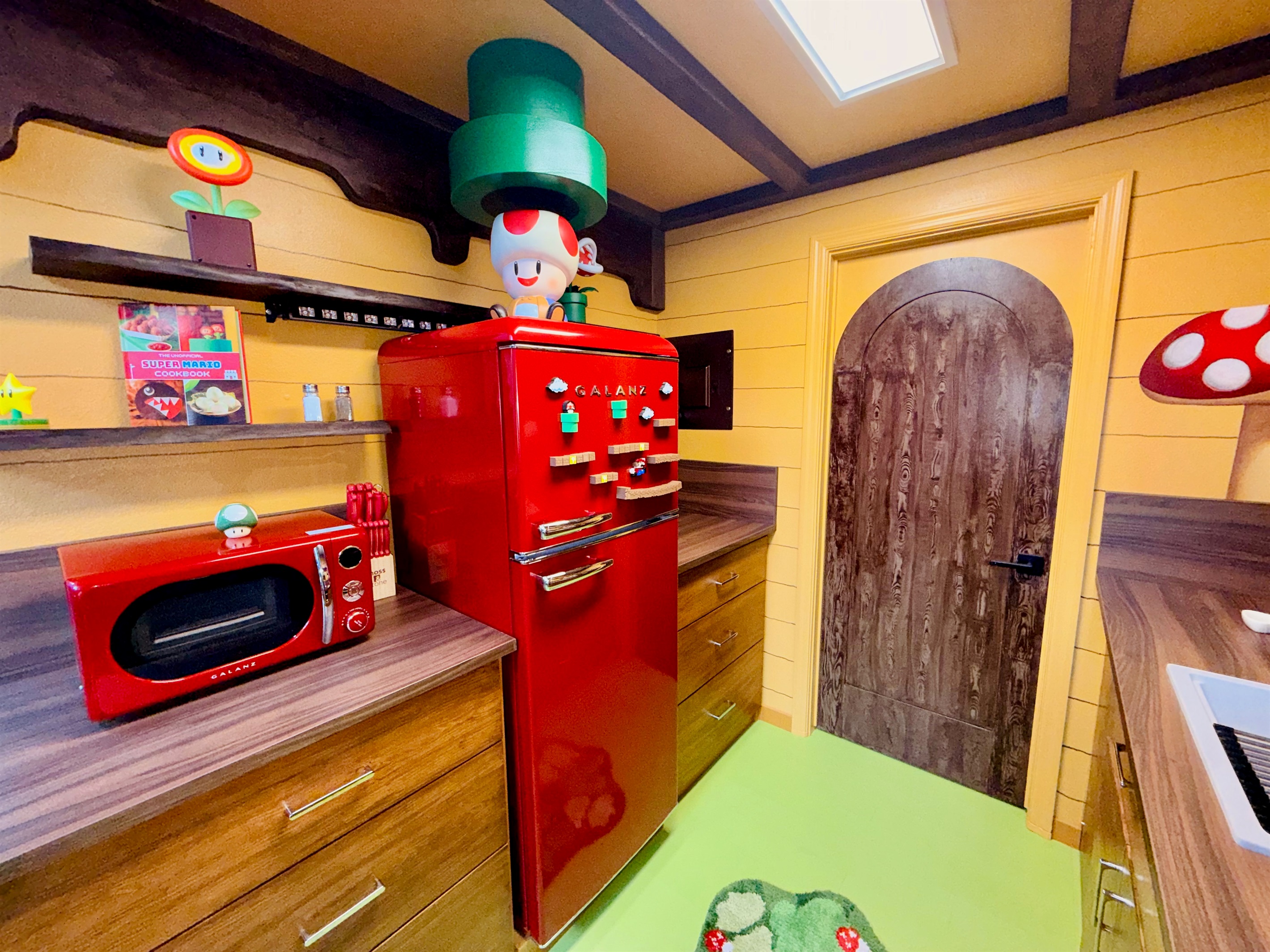 Retro red fridge and microwave corner in our Nintendo-inspired kitchen at Mario's Mini Mansion near Orlando, FL. Green pipe decor "toadstool cafe" vibe walls, and playful Mario accents bring joy to every cooking moment.