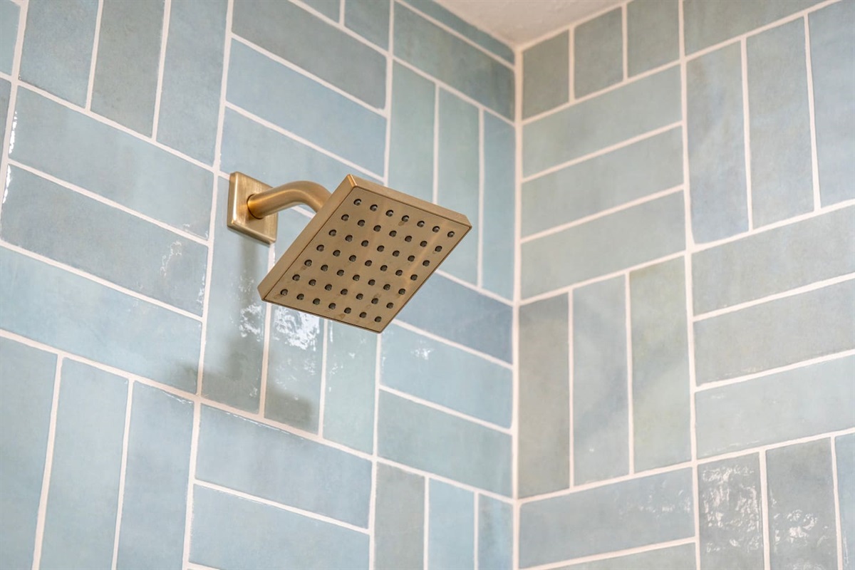 Spa-style rainfall shower with designer tile and modern brass fixtures