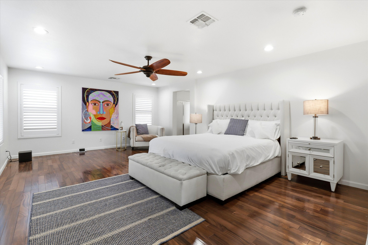 Bedroom with a large bed, sitting chair, wood floors, and plenty of space to settle in.
