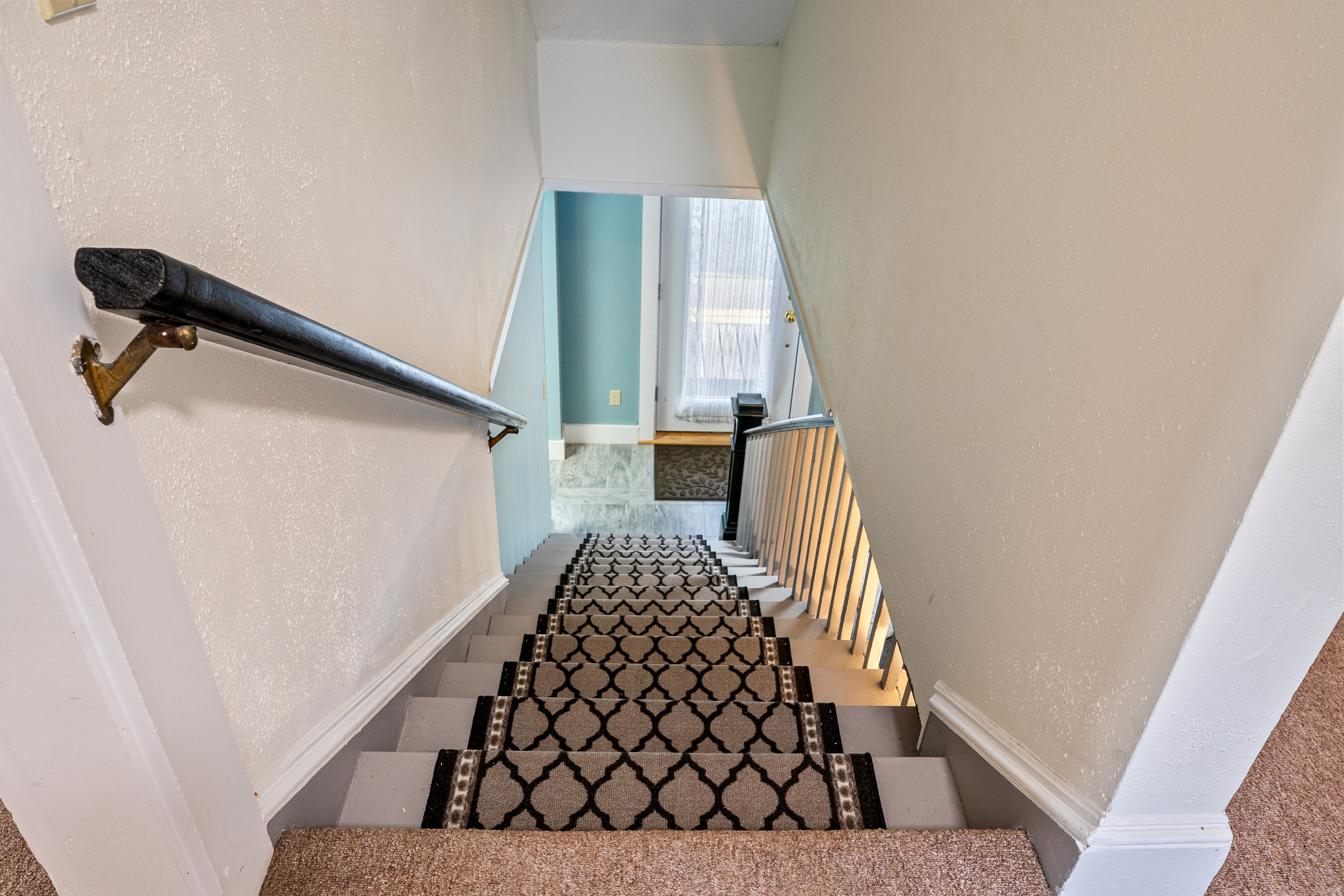 Enjoy a clear view of the home's open layout from the top landing. This downward perspective highlights the sturdy handrail and non-slip carpet runner, ensuring your group can navigate safely between the sleeping quarters and the main floor.