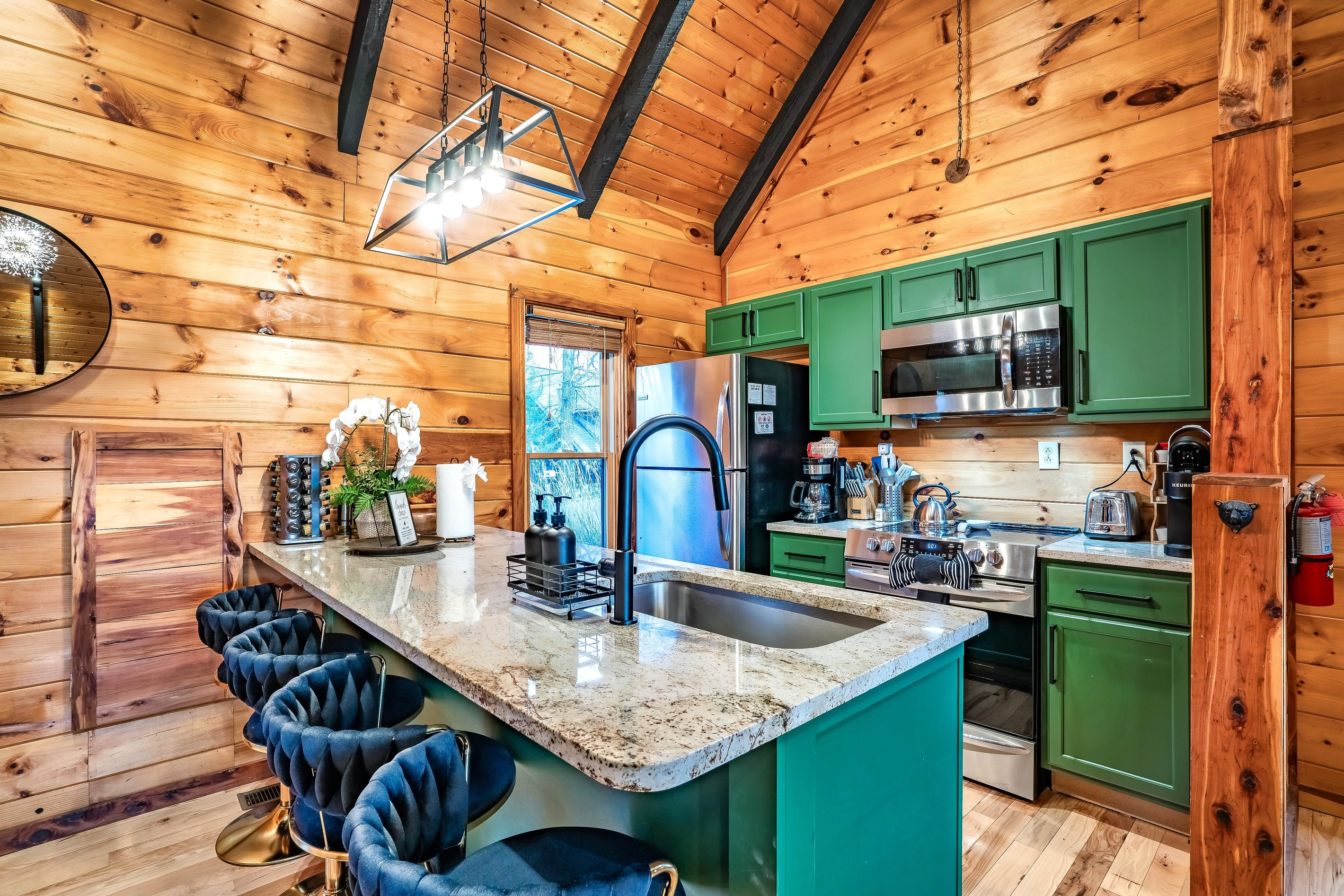 A warm, welcoming cabin kitchen with sleek countertops and bar seating, made for easy mornings, home-cooked meals, and relaxed evenings together in the comfort of your Tennessee mountain getaway.