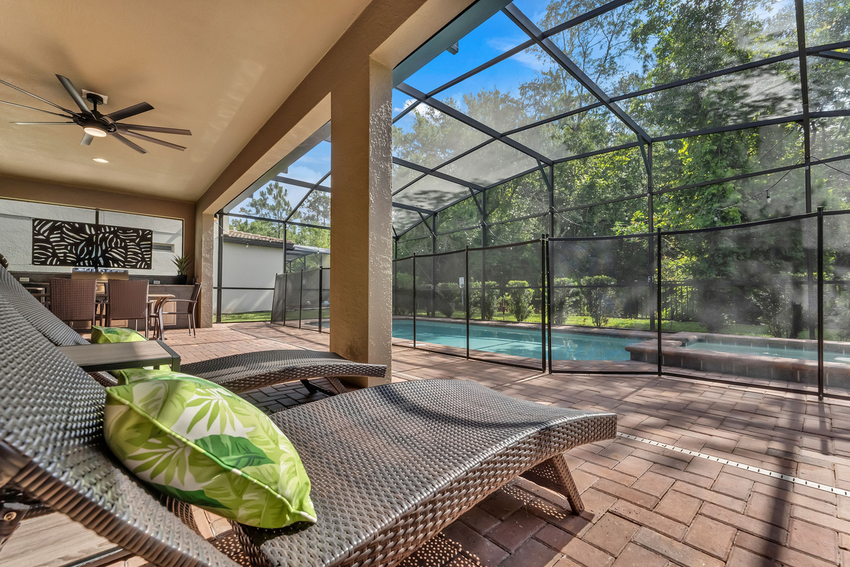 Patio with lounge chairs, table and additional chairs, grill, hot tub, pool, and sweeping views of the nature conservatory.
