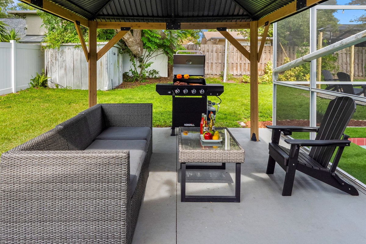 Enjoy a fresh-off-the-grill meal while staying cool under the gazebo. The rattan furniture offers comfort, while the layout keeps things social.