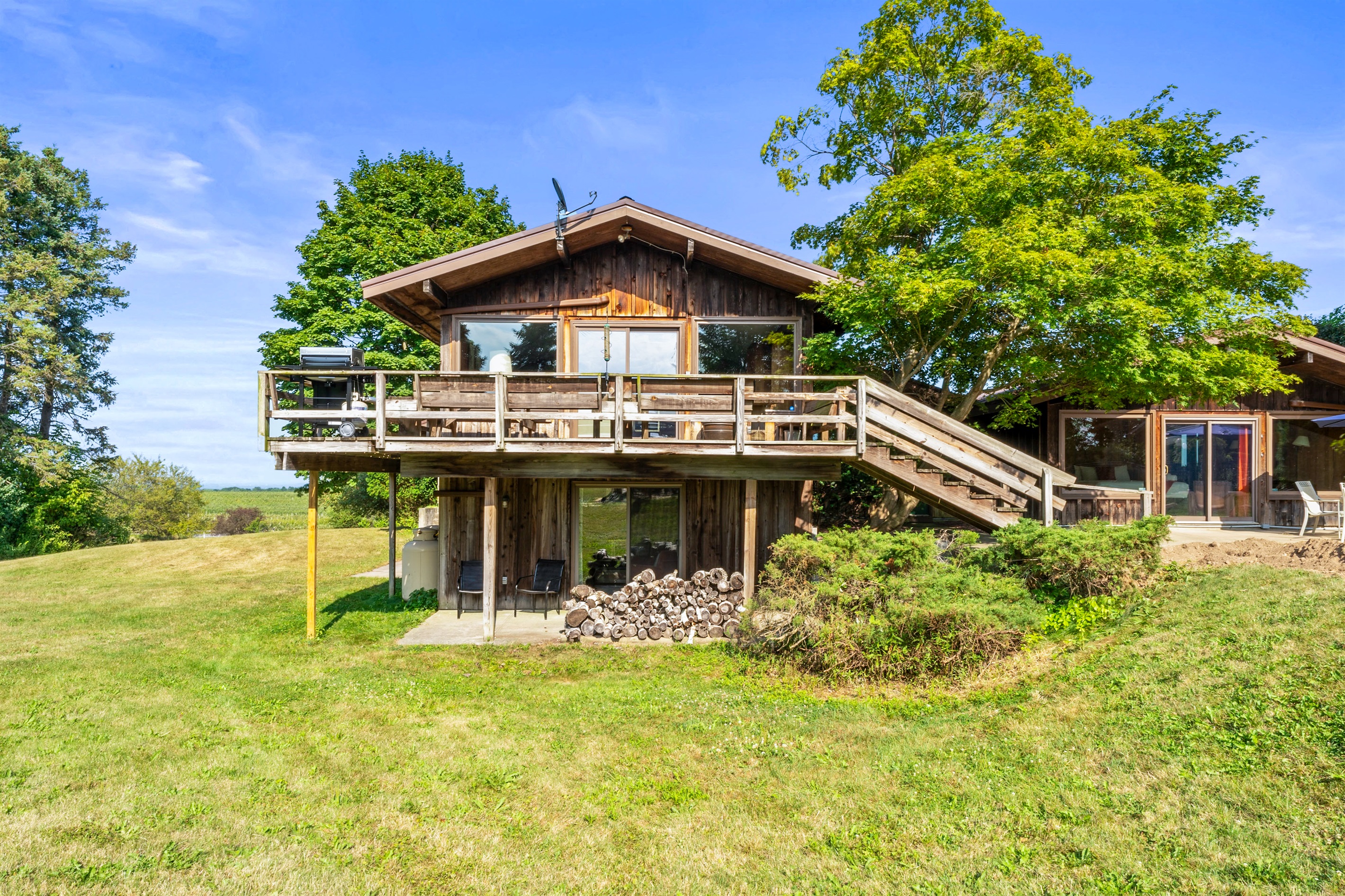 Rustic charm meets open skies at this countryside retreat! Featuring a spacious deck, floor-to-ceiling windows, and natural wood siding, this home is perfect for enjoying panoramic views and peaceful living.