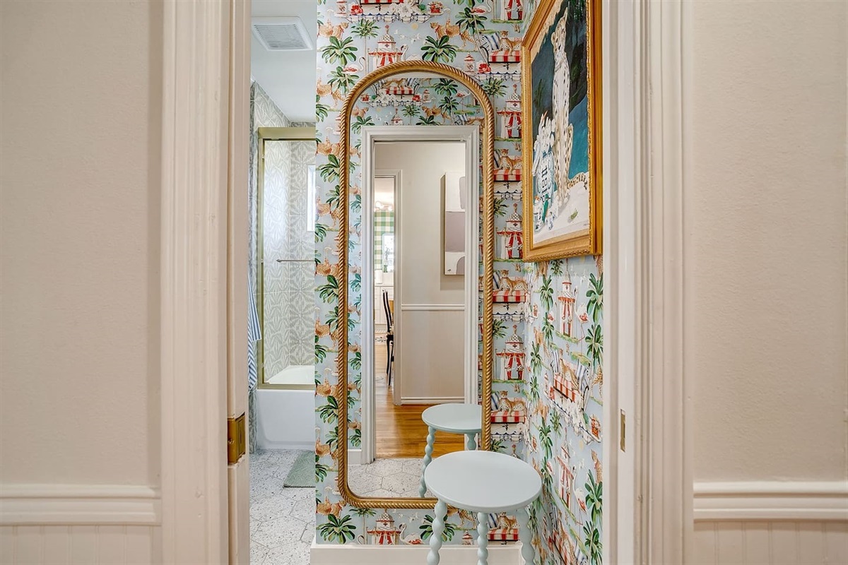 Front hall bath with personality- statement wallpaper, a full-size mirror for final touch-ups, and a styled foyer nook that feels more boutique than basic.