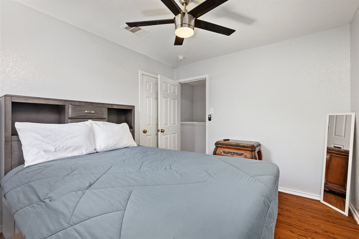 Queen bedroom with dresser for clothing storage, ceiling fan, and comfortable gray bedding. Extra pillows and blankets provided. Clean, well-furnished, and private near Randolph AFB and San Antonio attractions.