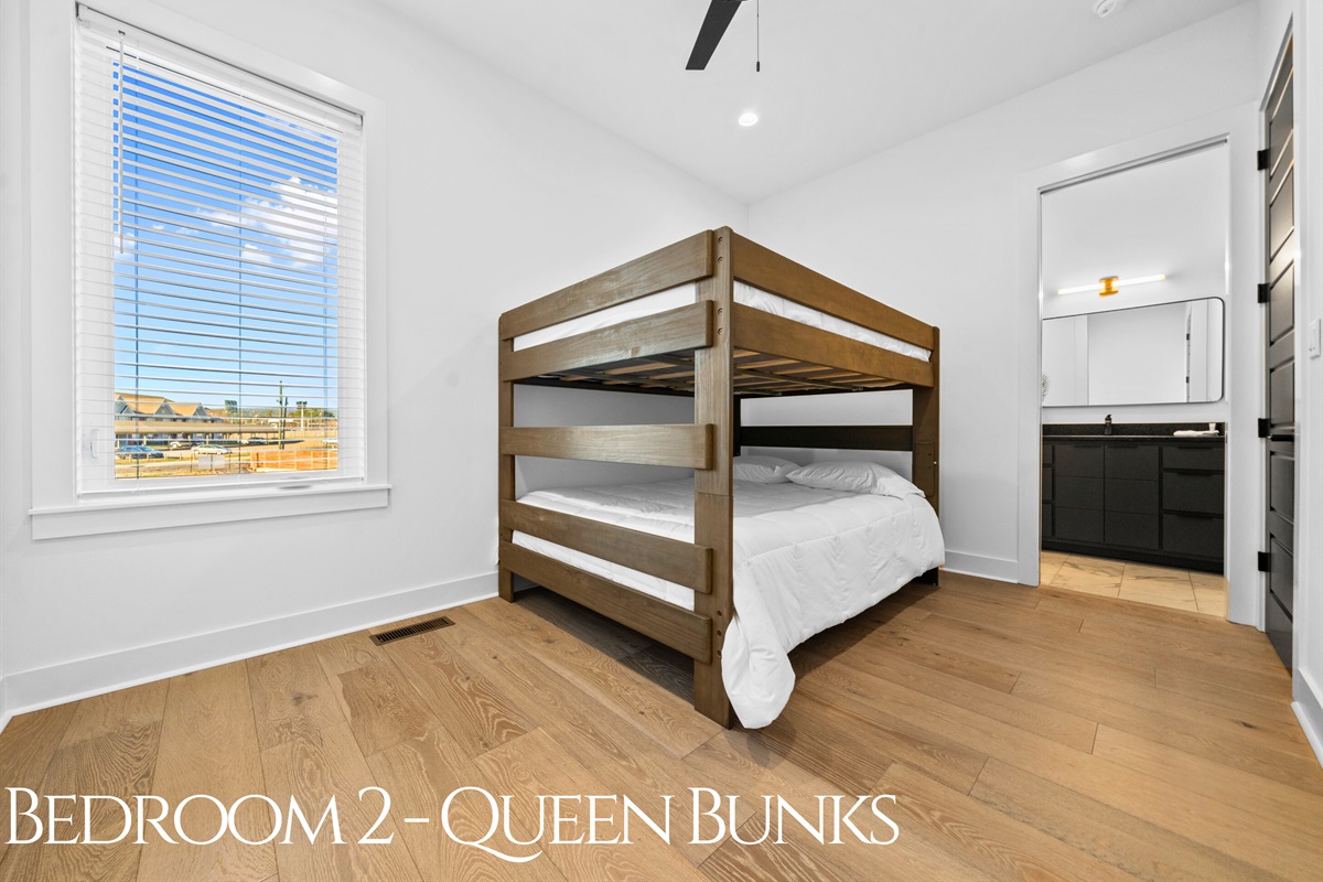 A bright and inviting queen bunk room with clean lines, cozy bedding, and plenty of space, designed to make every guest feel right at home.