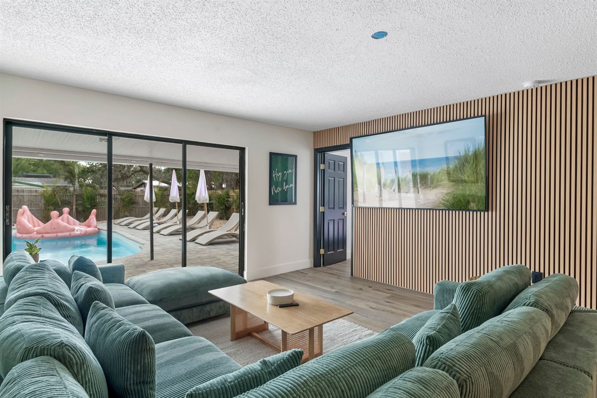 Stylish Living Room with 85-Inch TV. Acoustical accent wall, open to the kitchen and the pool 