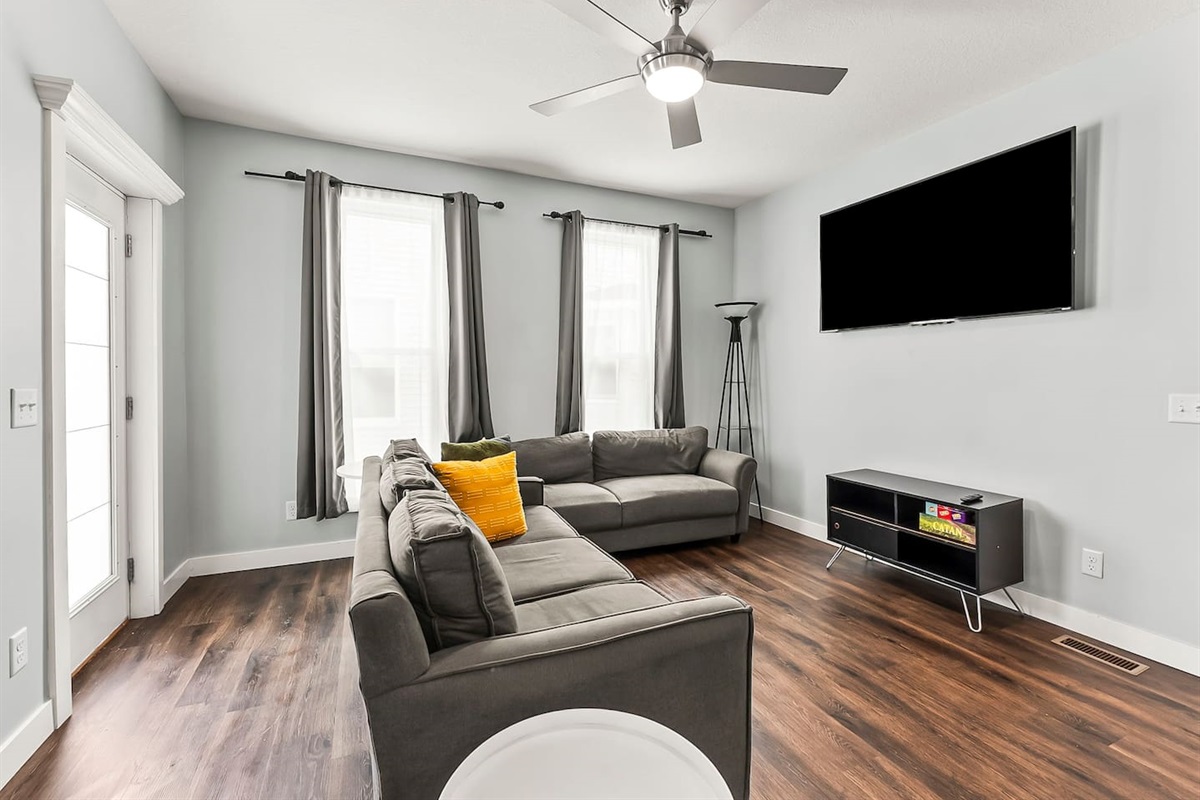 Unwind in the cozy living area featuring plush sofas, a large wall-mounted TV, and plenty of natural light.